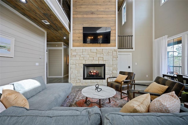 living area with visible vents, wood walls, a fireplace, and a towering ceiling