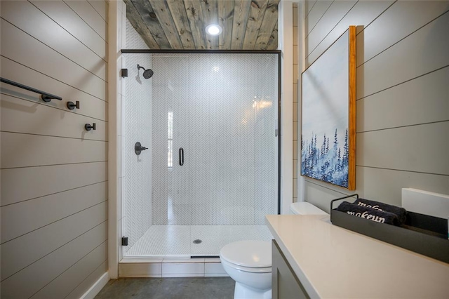 full bath featuring a stall shower, wooden walls, toilet, and vanity