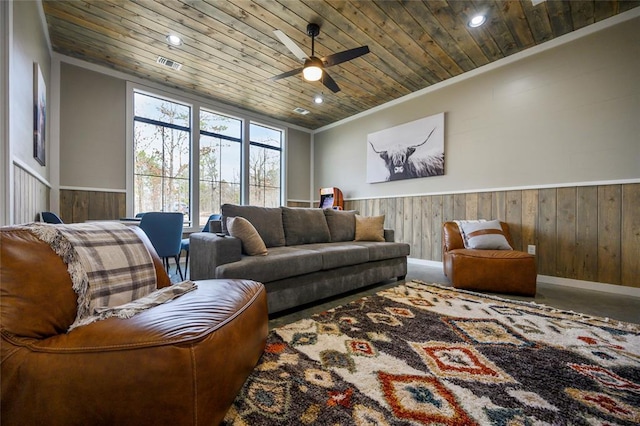 living area with a wainscoted wall, visible vents, and wood ceiling