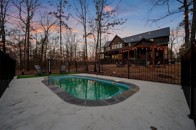 pool at dusk with a patio, fence, and a fenced in pool