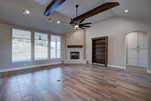 unfurnished living room featuring vaulted ceiling with beams and a brick fireplace