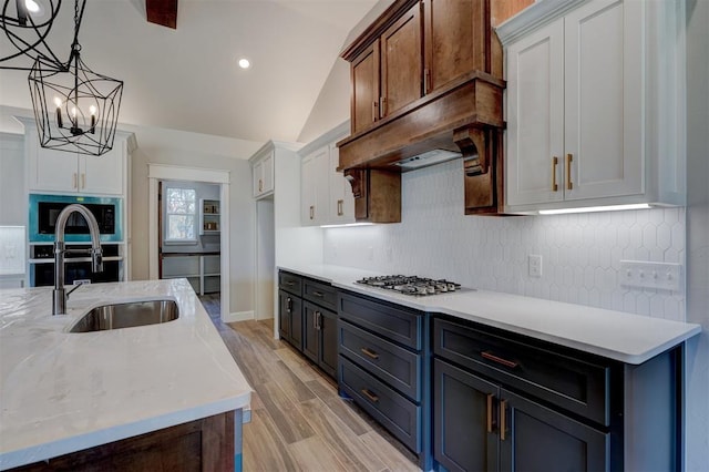 kitchen featuring decorative light fixtures, light hardwood / wood-style flooring, a chandelier, white cabinetry, and lofted ceiling