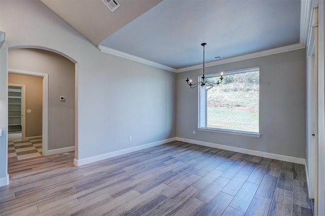 empty room with ornamental molding, light wood-type flooring, vaulted ceiling, and a notable chandelier