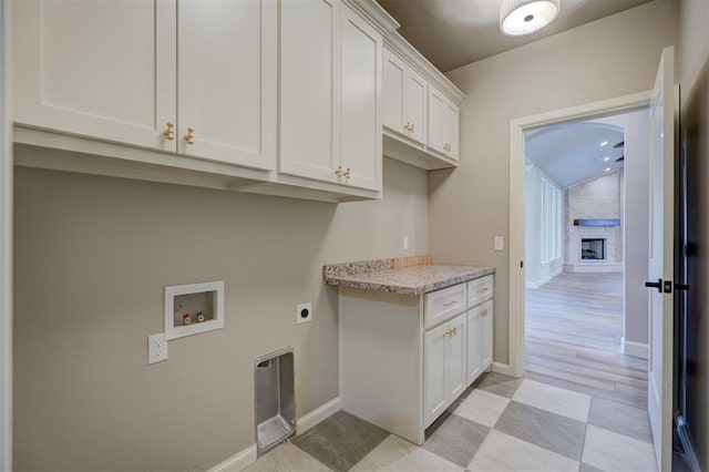 laundry area featuring cabinets, hookup for a washing machine, a fireplace, and hookup for an electric dryer