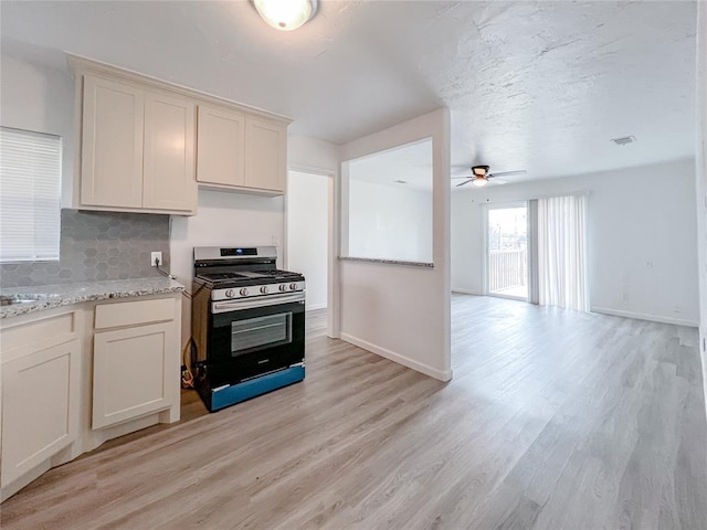 kitchen featuring decorative backsplash, light stone countertops, range with gas cooktop, ceiling fan, and light hardwood / wood-style floors