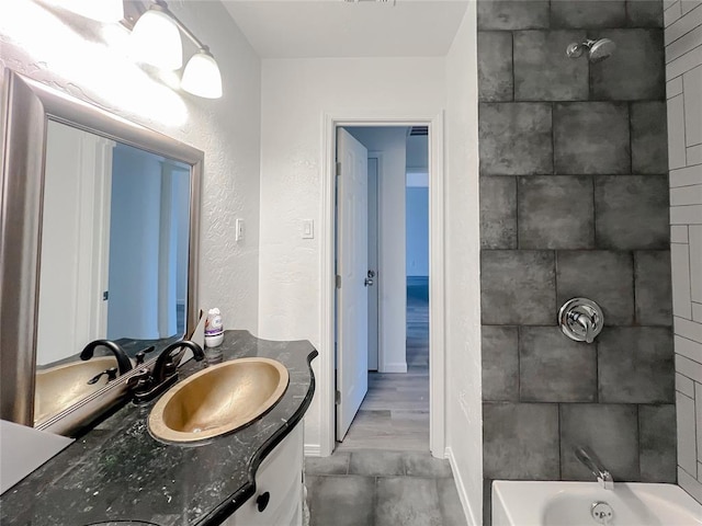 bathroom featuring tiled shower / bath combo and vanity