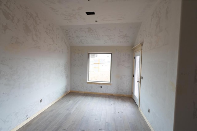 spare room with vaulted ceiling, wood finished floors, and baseboards