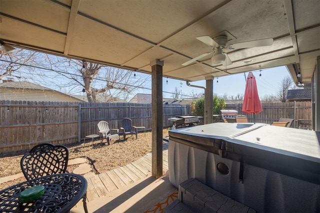 wooden terrace featuring ceiling fan and a hot tub