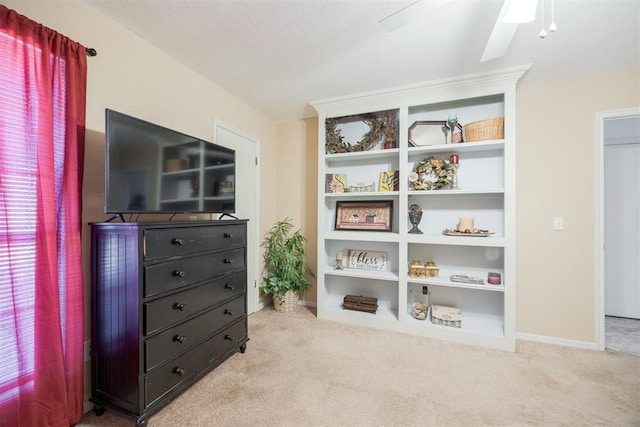 interior space featuring built in shelves, ceiling fan, and light carpet