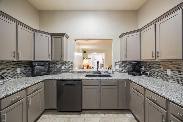 kitchen with tasteful backsplash, dishwasher, light stone countertops, gray cabinets, and a sink