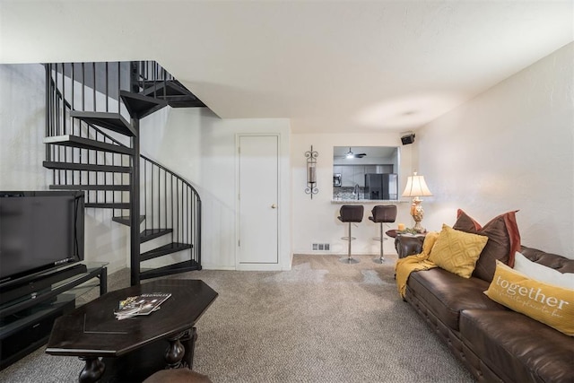 living room with carpet floors, visible vents, and stairs