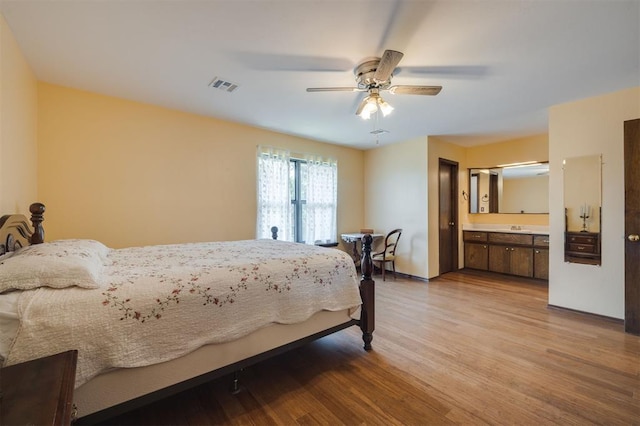 bedroom featuring ensuite bathroom, sink, ceiling fan, and light wood-type flooring