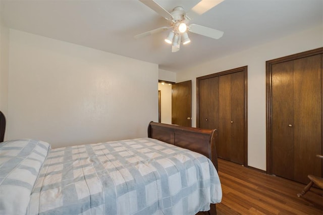 bedroom featuring ceiling fan, wood-type flooring, and multiple closets