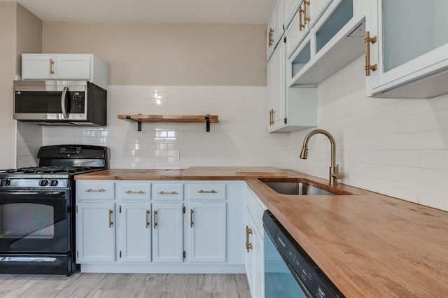 kitchen featuring gas stove, butcher block countertops, white cabinetry, and sink