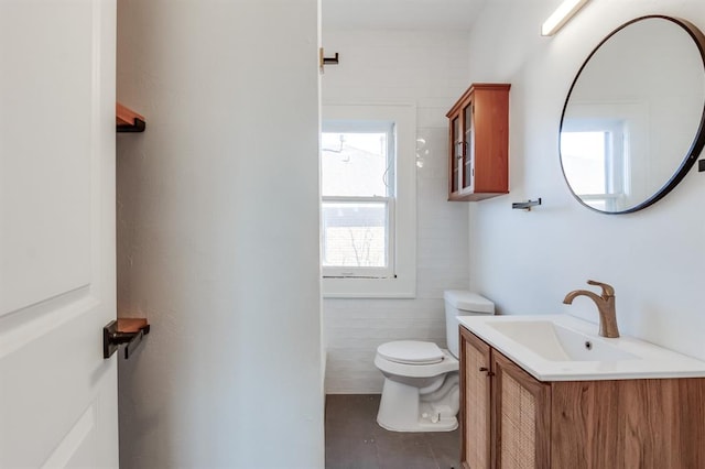 bathroom with vanity, toilet, and tile walls