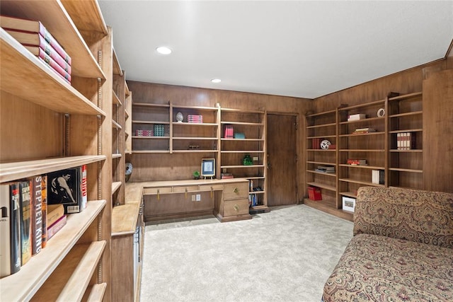 carpeted office featuring wood walls and built in desk