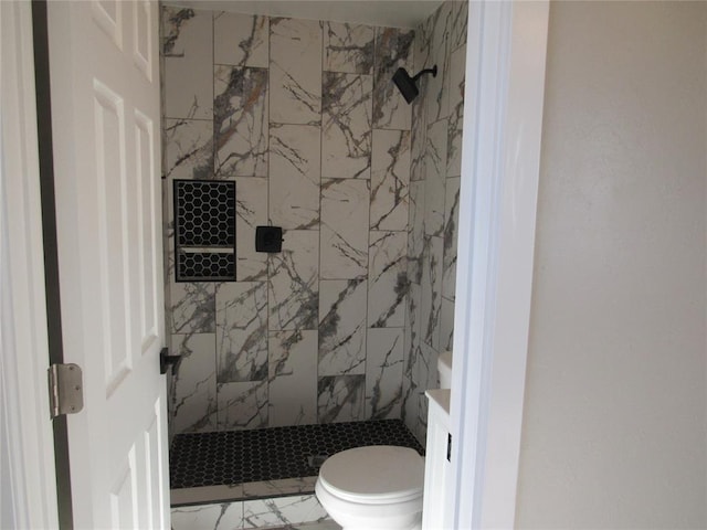 bathroom featuring a tile shower and toilet