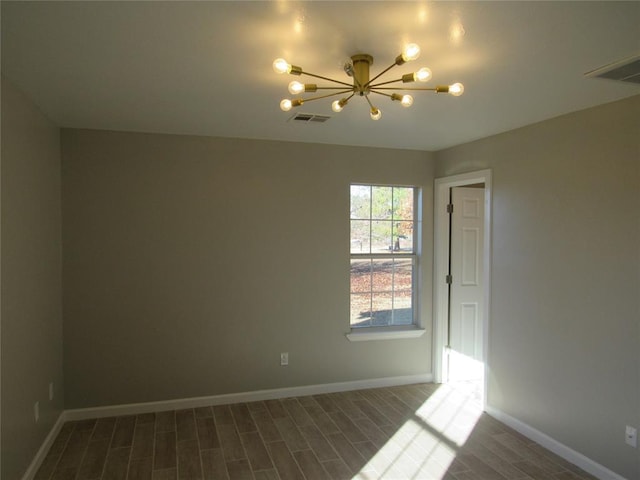 spare room with dark hardwood / wood-style flooring and a chandelier