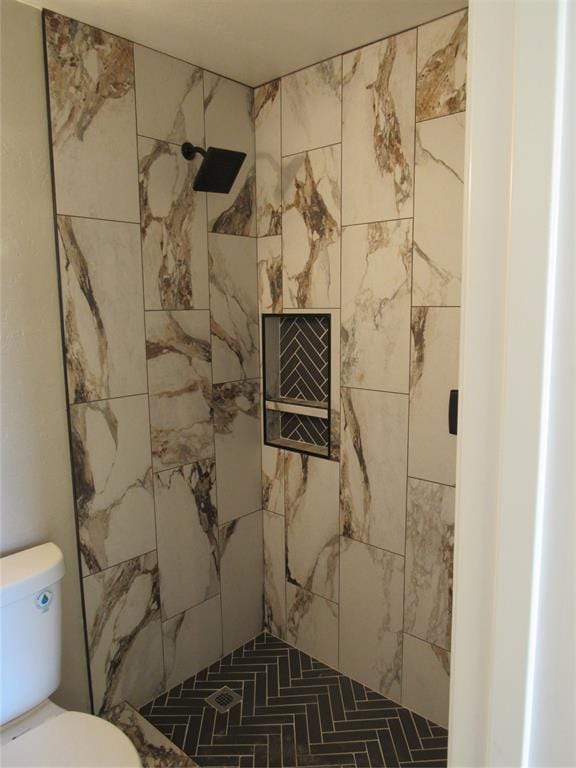 bathroom with tiled shower and toilet