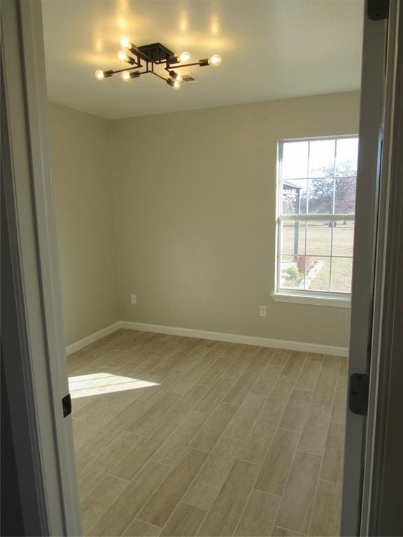 unfurnished room featuring a chandelier