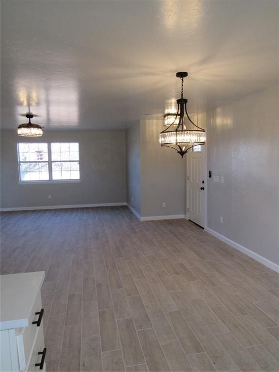 spare room with wood-type flooring and an inviting chandelier