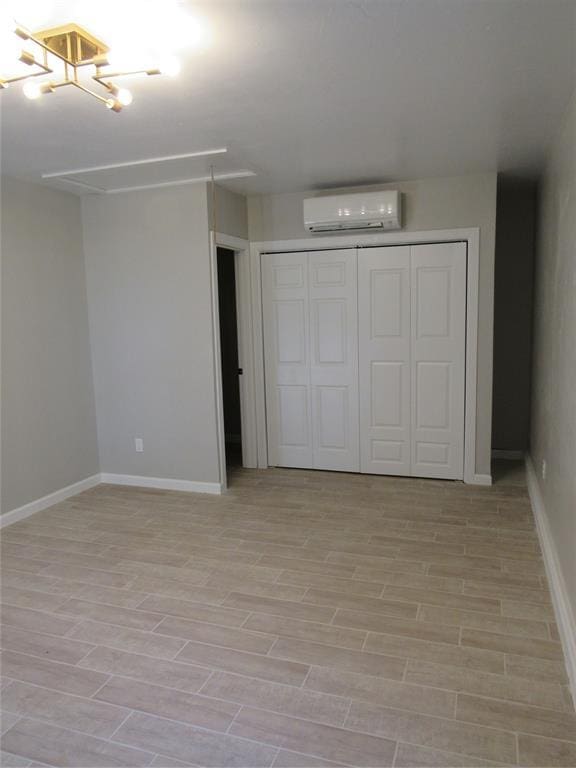 unfurnished bedroom featuring an AC wall unit, a closet, and light wood-type flooring