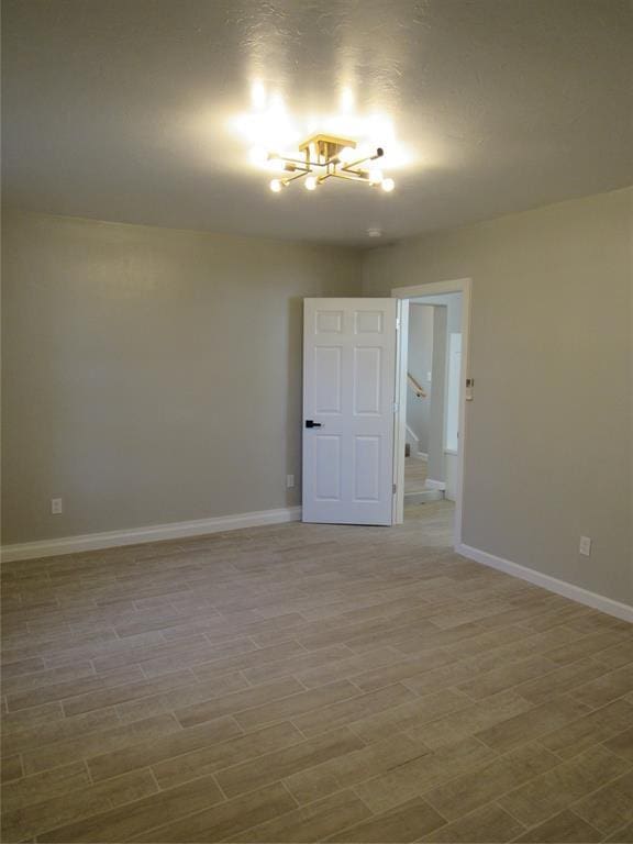 spare room featuring hardwood / wood-style flooring and a notable chandelier