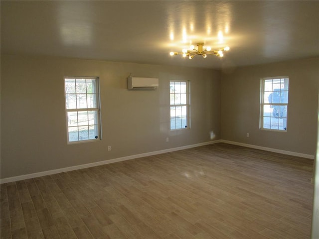 empty room featuring a wall unit AC, dark hardwood / wood-style flooring, and an inviting chandelier