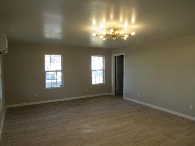 spare room featuring an AC wall unit, a chandelier, and hardwood / wood-style flooring