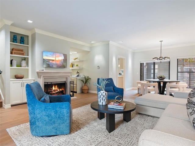 living room featuring a chandelier, light hardwood / wood-style floors, built in features, and ornamental molding