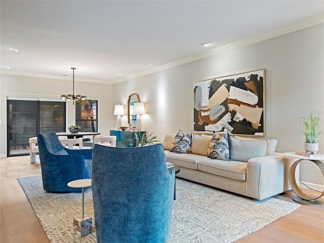 living room with crown molding, a chandelier, and light wood-type flooring