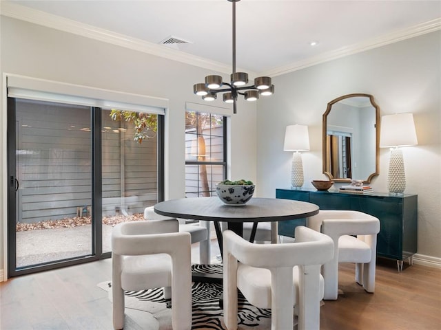 dining area featuring crown molding, a notable chandelier, and light wood-type flooring