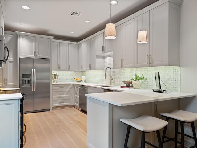 kitchen with kitchen peninsula, a kitchen bar, decorative light fixtures, and built in fridge