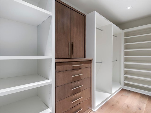 walk in closet with light hardwood / wood-style flooring