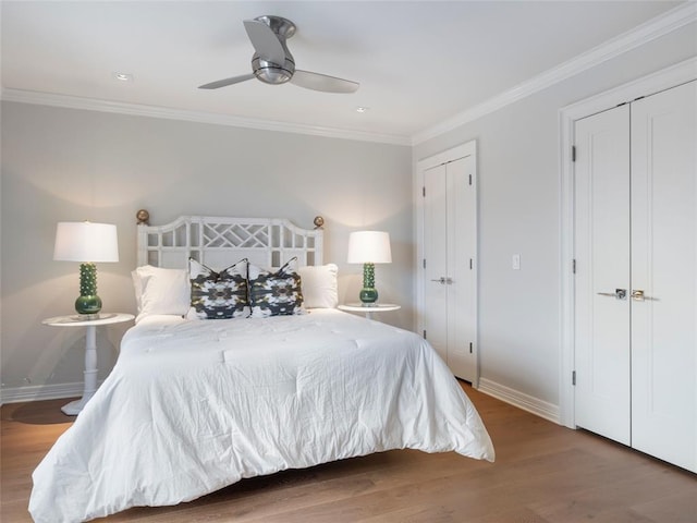 bedroom with ceiling fan, wood-type flooring, crown molding, and multiple closets