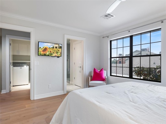 bedroom featuring washer / dryer, connected bathroom, light hardwood / wood-style floors, and ornamental molding