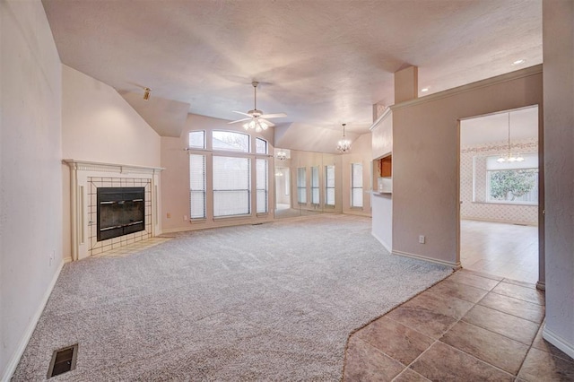 unfurnished living room with carpet flooring, ceiling fan with notable chandelier, a tile fireplace, and lofted ceiling