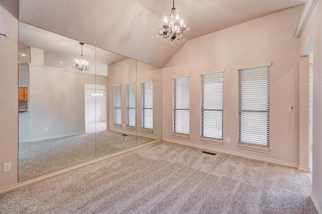 carpeted empty room with lofted ceiling and a chandelier