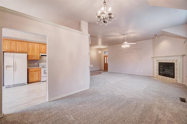 unfurnished living room featuring a fireplace, light colored carpet, and ceiling fan with notable chandelier