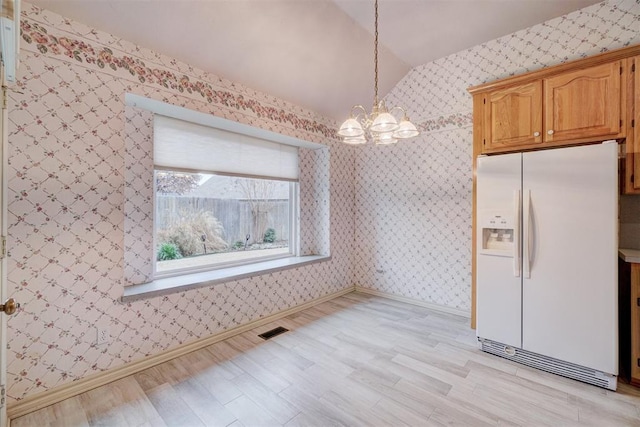 kitchen with light wood-type flooring, vaulted ceiling, white refrigerator with ice dispenser, a notable chandelier, and hanging light fixtures