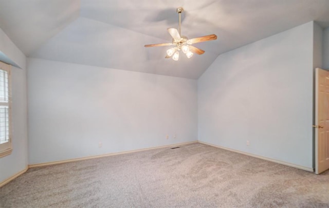 carpeted spare room featuring ceiling fan and vaulted ceiling