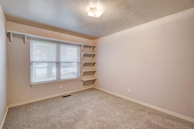 carpeted spare room featuring a textured ceiling