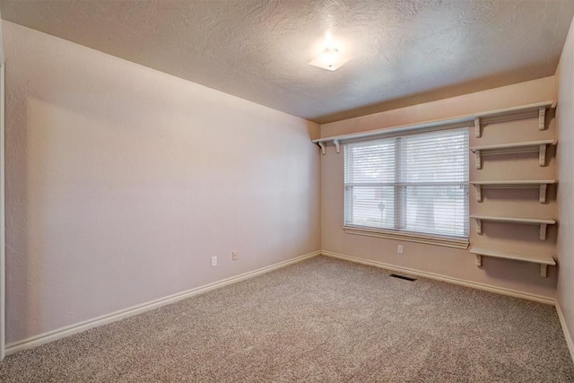 carpeted spare room with a textured ceiling