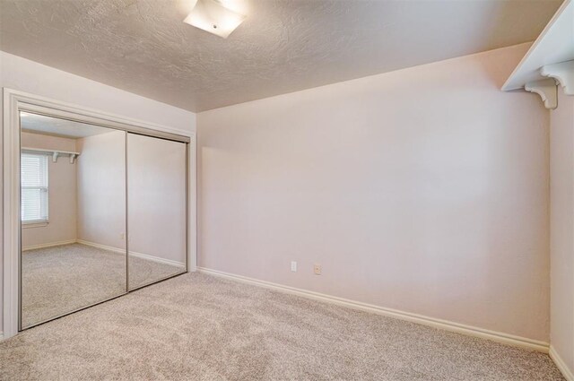 unfurnished bedroom featuring a closet, carpet, and a textured ceiling