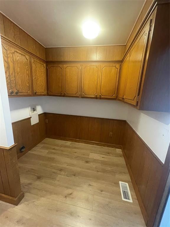 laundry room with wood walls, hookup for a washing machine, cabinets, and light hardwood / wood-style floors