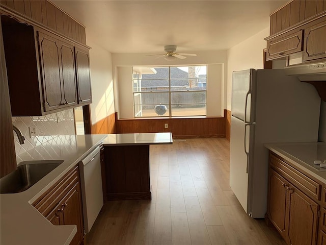 kitchen featuring white appliances, sink, ceiling fan, light hardwood / wood-style floors, and kitchen peninsula