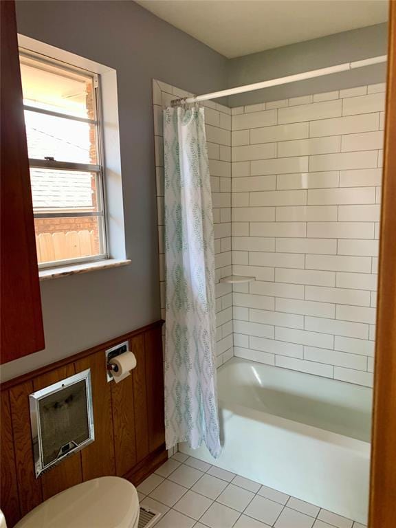 bathroom with tile patterned flooring, toilet, shower / bathtub combination with curtain, and wooden walls