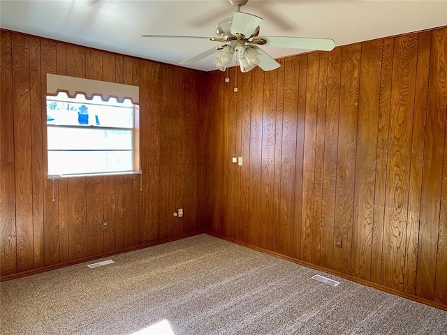 unfurnished room with ceiling fan, wooden walls, and carpet floors