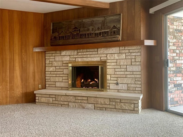 room details featuring carpet, a stone fireplace, beamed ceiling, and wood walls