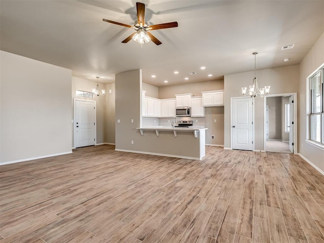 kitchen with appliances with stainless steel finishes, open floor plan, white cabinets, and a breakfast bar area